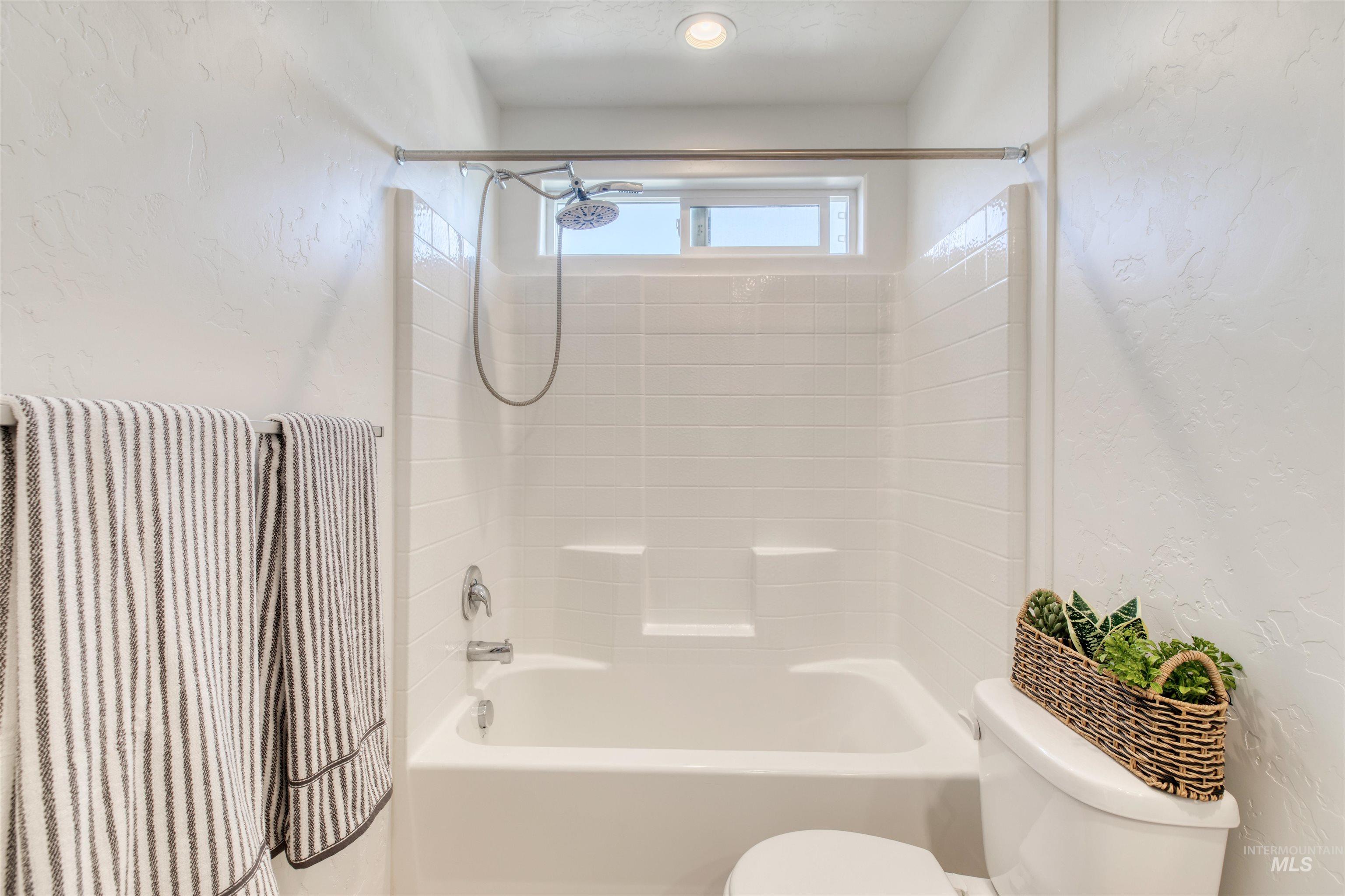 Bathroom with a textured wall and washtub / shower combination