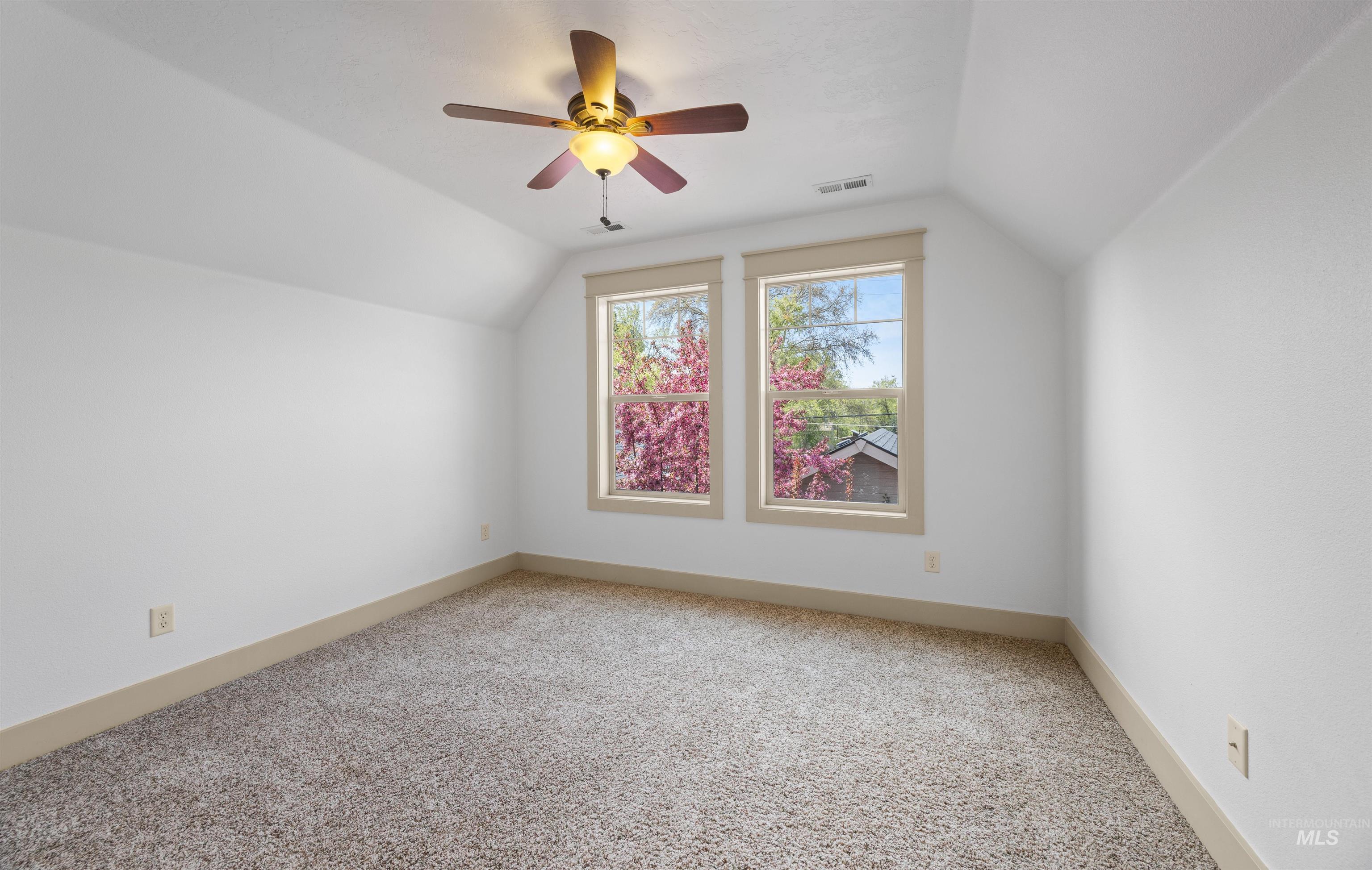 Bonus room featuring light colored carpet, vaulted ceiling, and ceiling fan