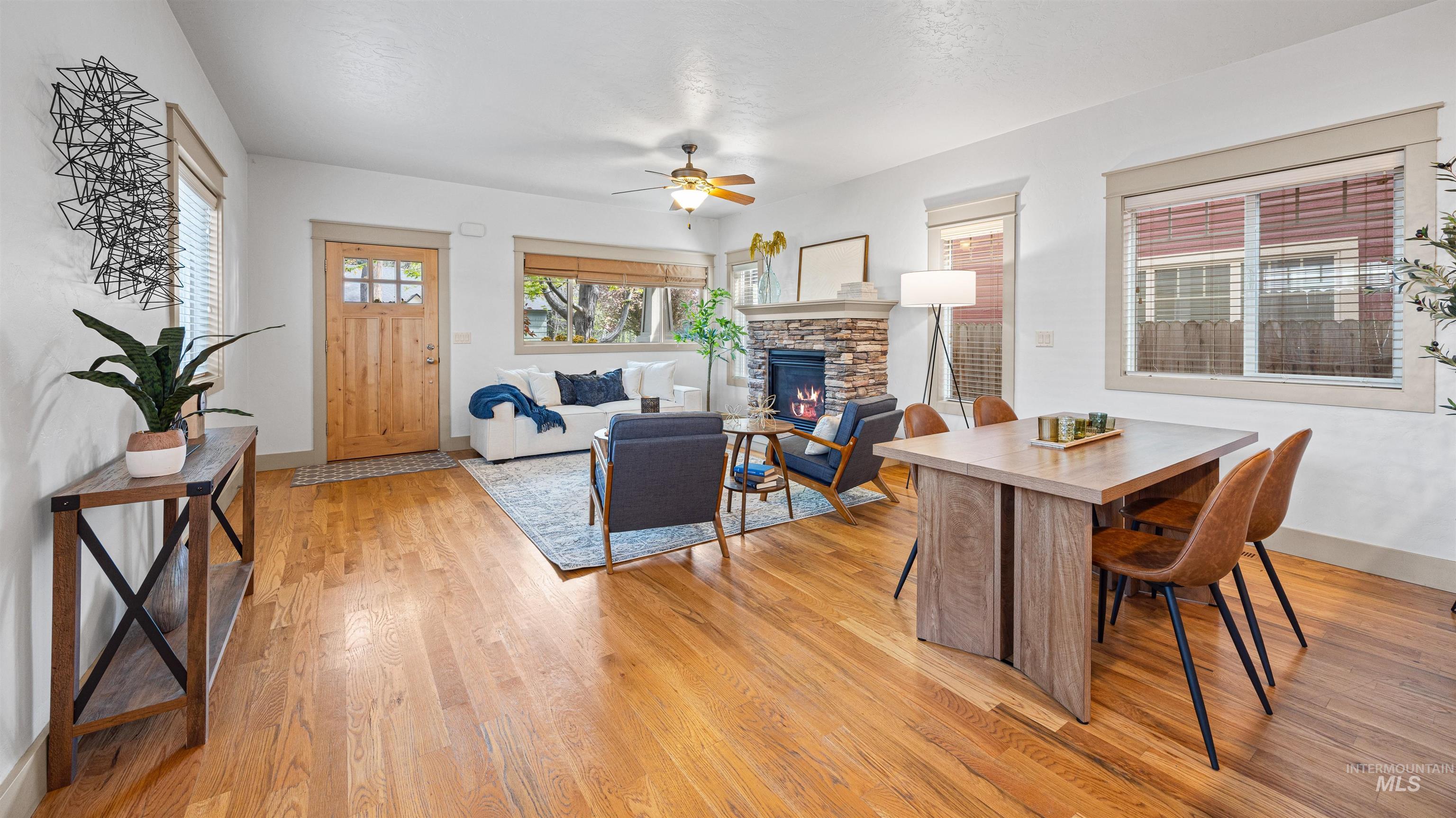 Dining area with ceiling fan, a fireplace, and light wood-style floors