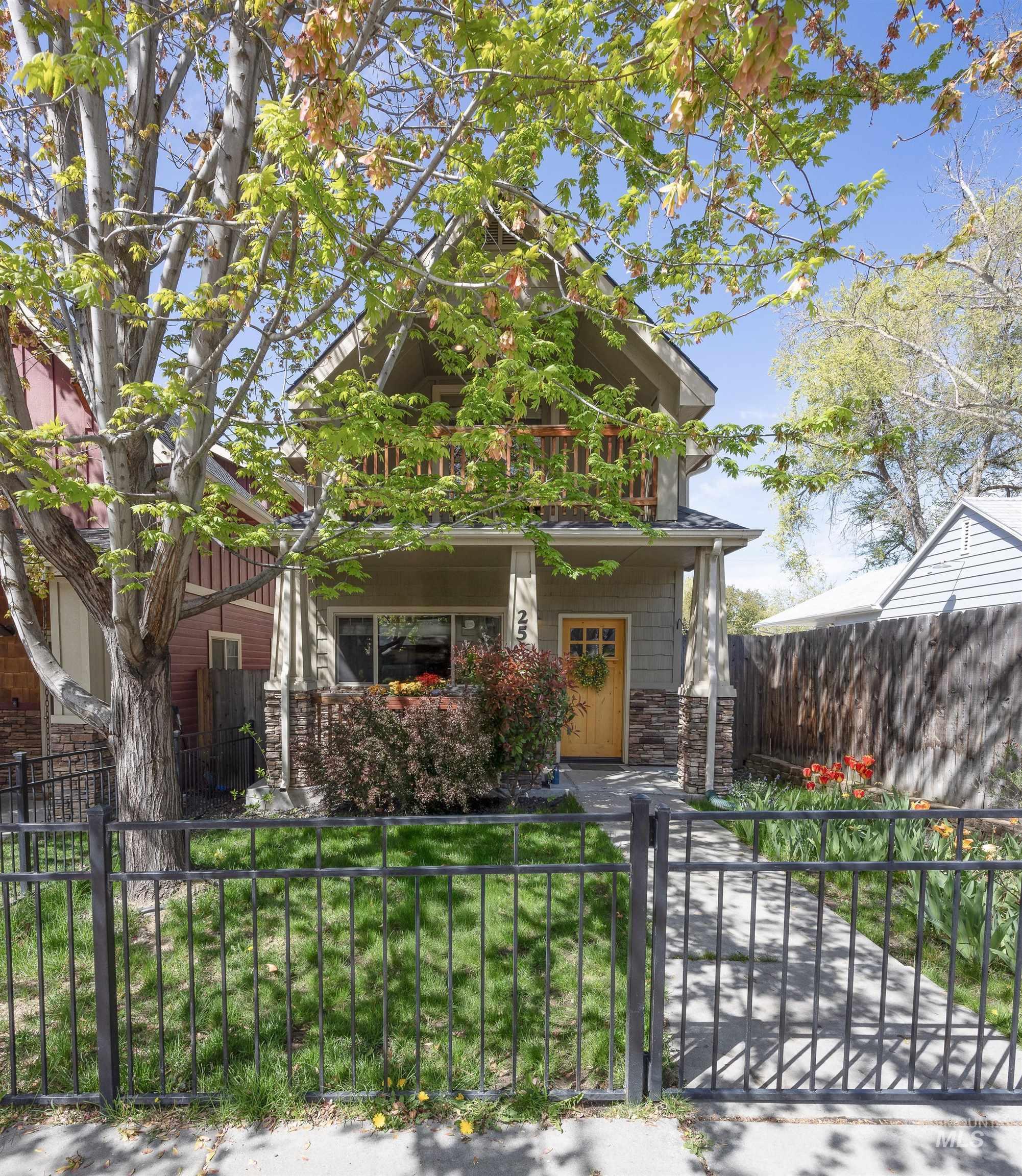 Craftsman-style house featuring stone siding, a fenced front yard, and a gate
