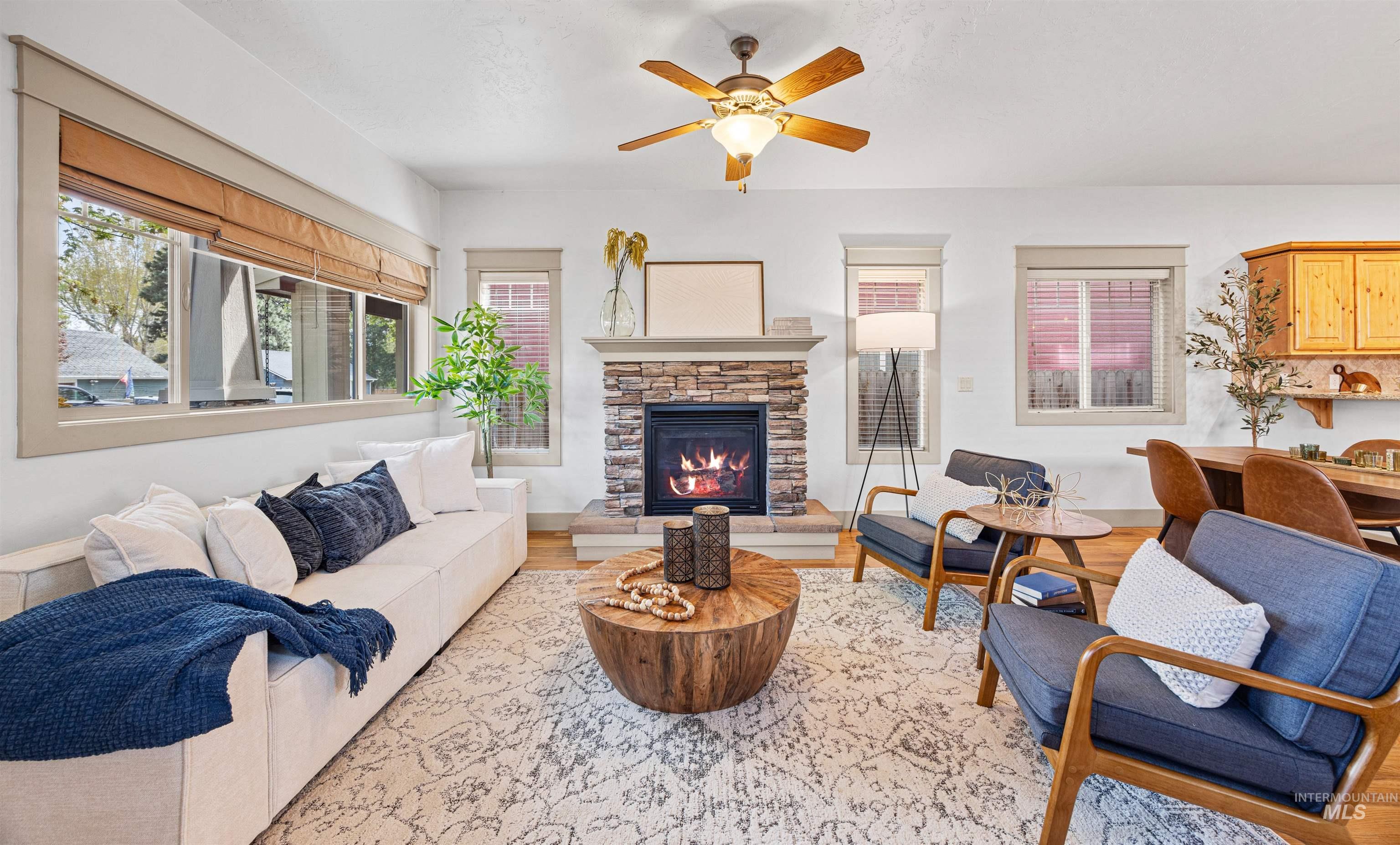 Living room with wood finished floors, a fireplace, and a ceiling fan