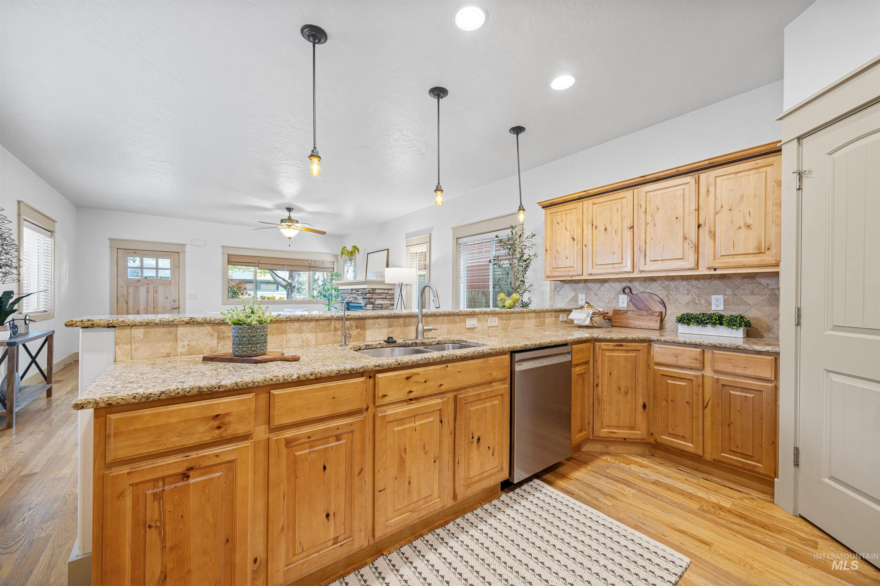 Kitchen with light wood-style flooring, light stone countertops, hanging light fixtures, decorative backsplash, and recessed lighting