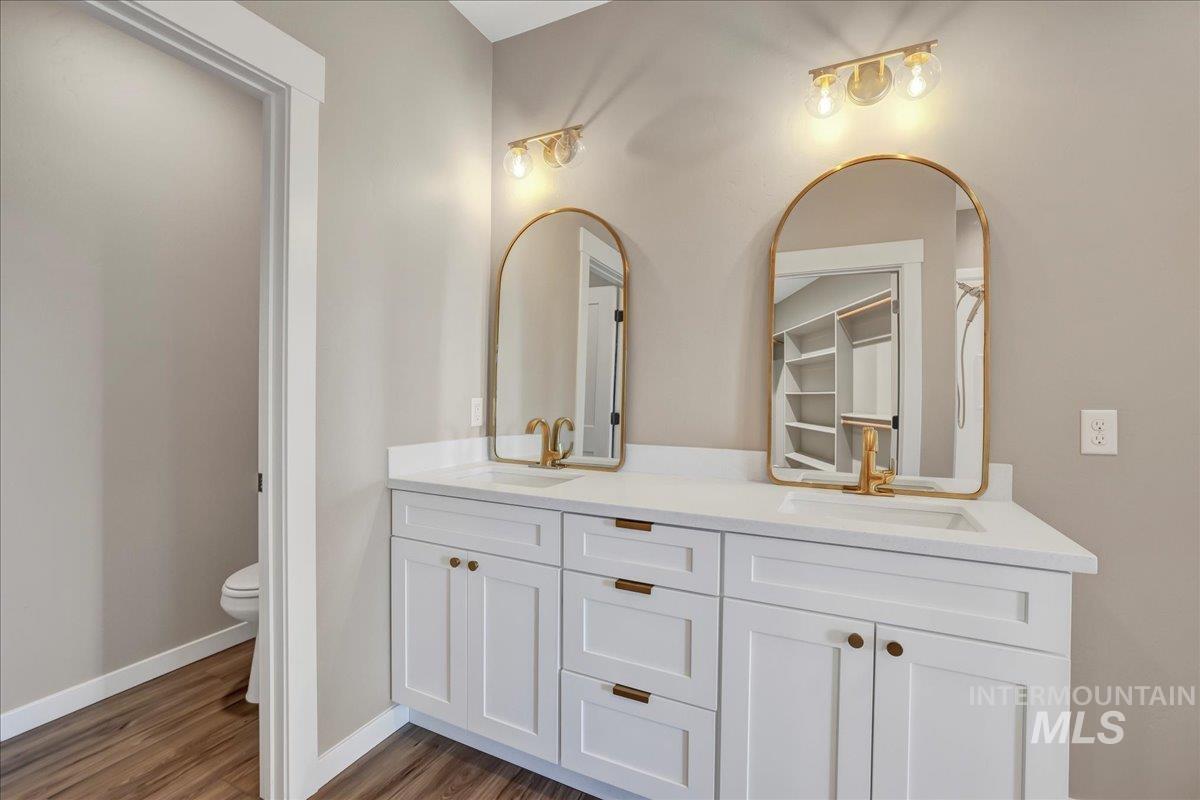 Full bathroom featuring double vanity and dark wood-style flooring