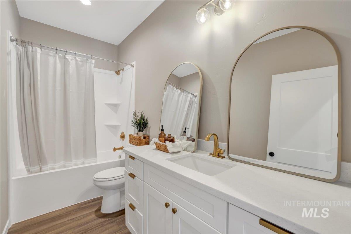 Full bathroom featuring shower / tub combo, dark wood-type flooring, and vanity