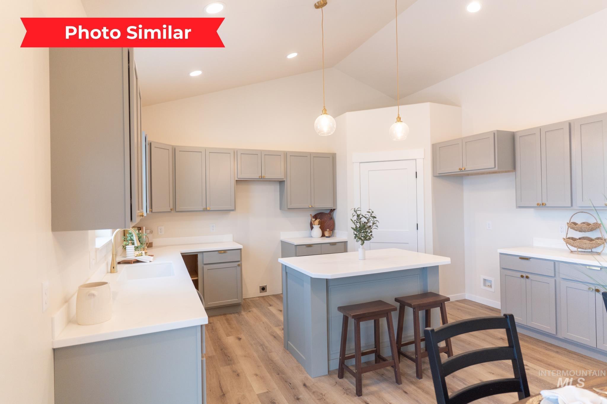Kitchen with gray cabinets, a breakfast bar, pendant lighting, and high vaulted ceiling