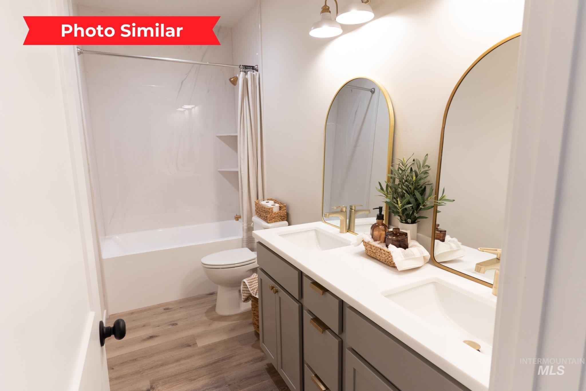 Bathroom featuring light wood-type flooring, double vanity, and shower / bath combination with curtain