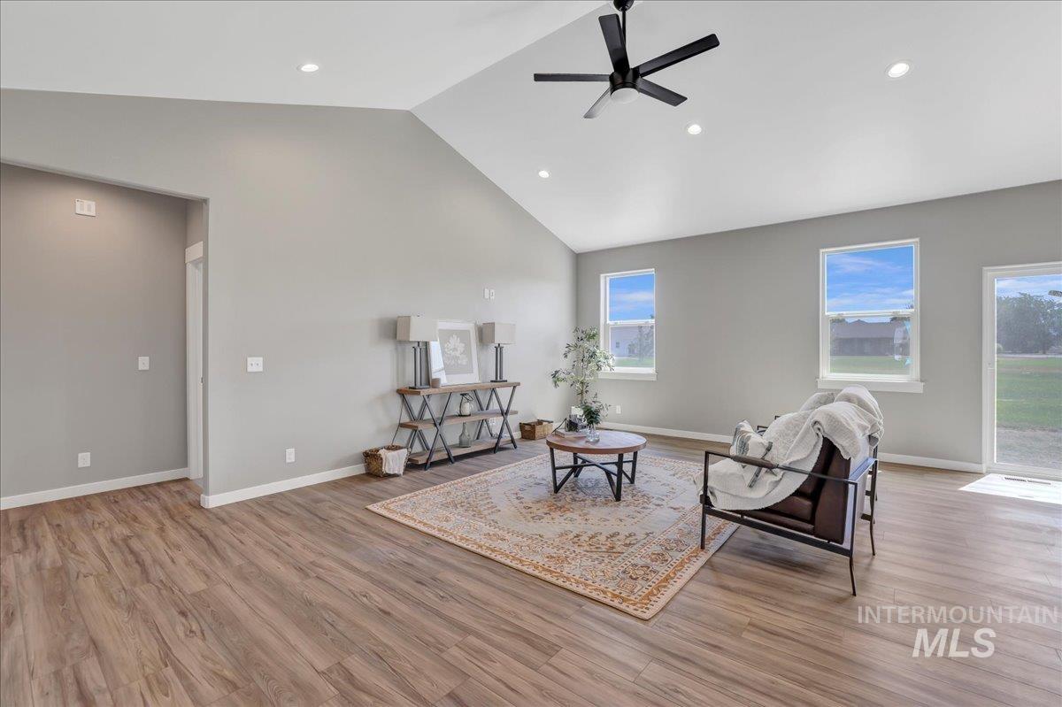 Sitting room with light wood-type flooring, high vaulted ceiling, recessed lighting, and ceiling fan