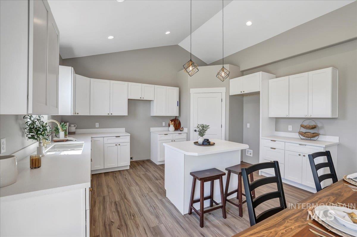 Kitchen featuring a kitchen bar, decorative light fixtures, a center island, dark wood finished floors, and white cabinets