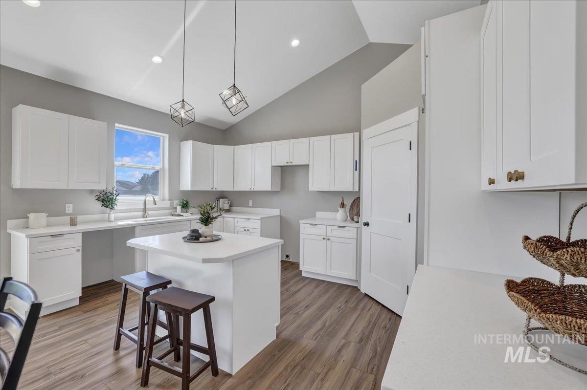 Kitchen featuring pendant lighting, light wood-style floors, white cabinetry, a kitchen bar, and a kitchen island
