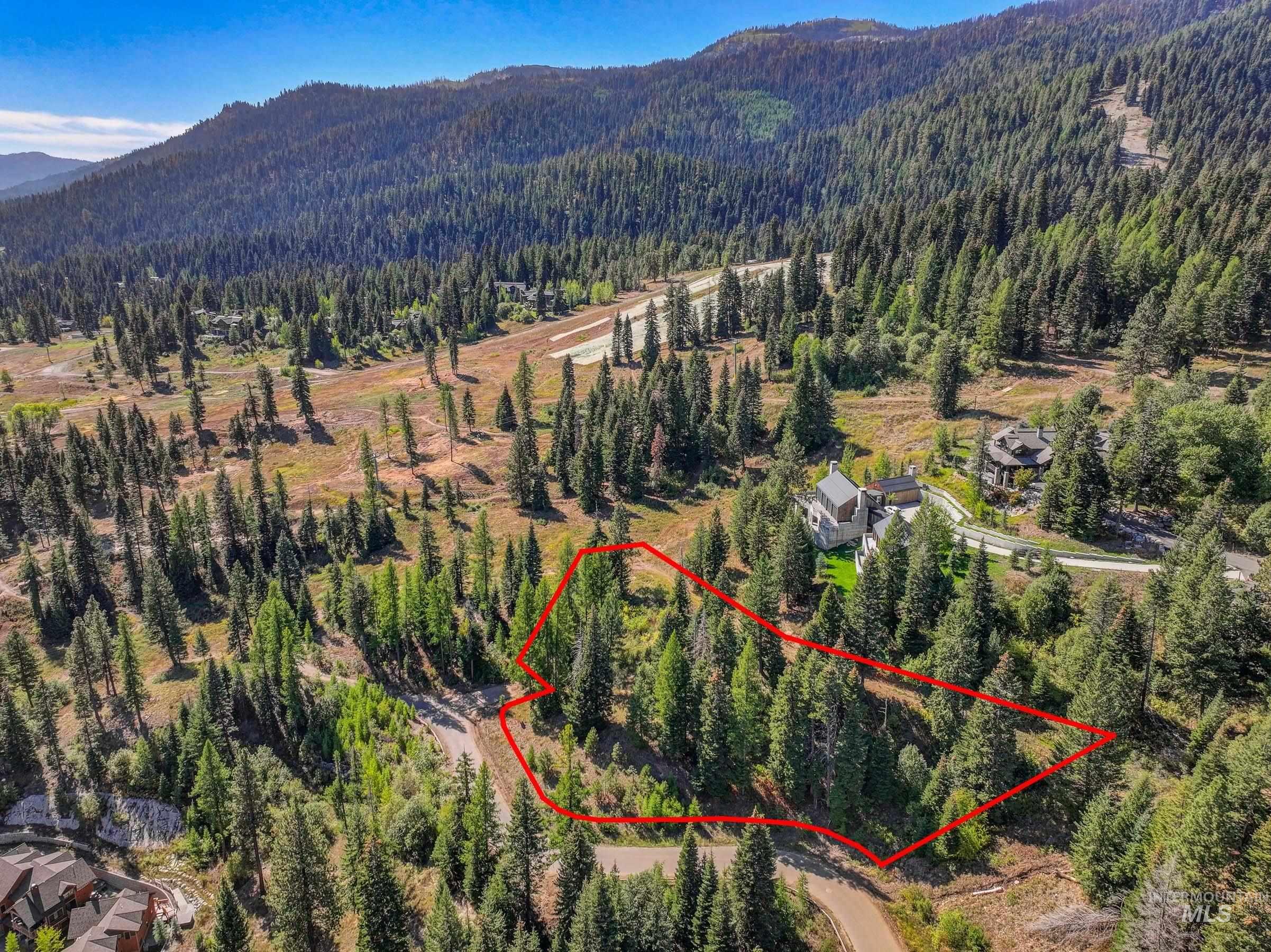 Aerial view of property and surrounding area with property parcel outlined and resort backdrop