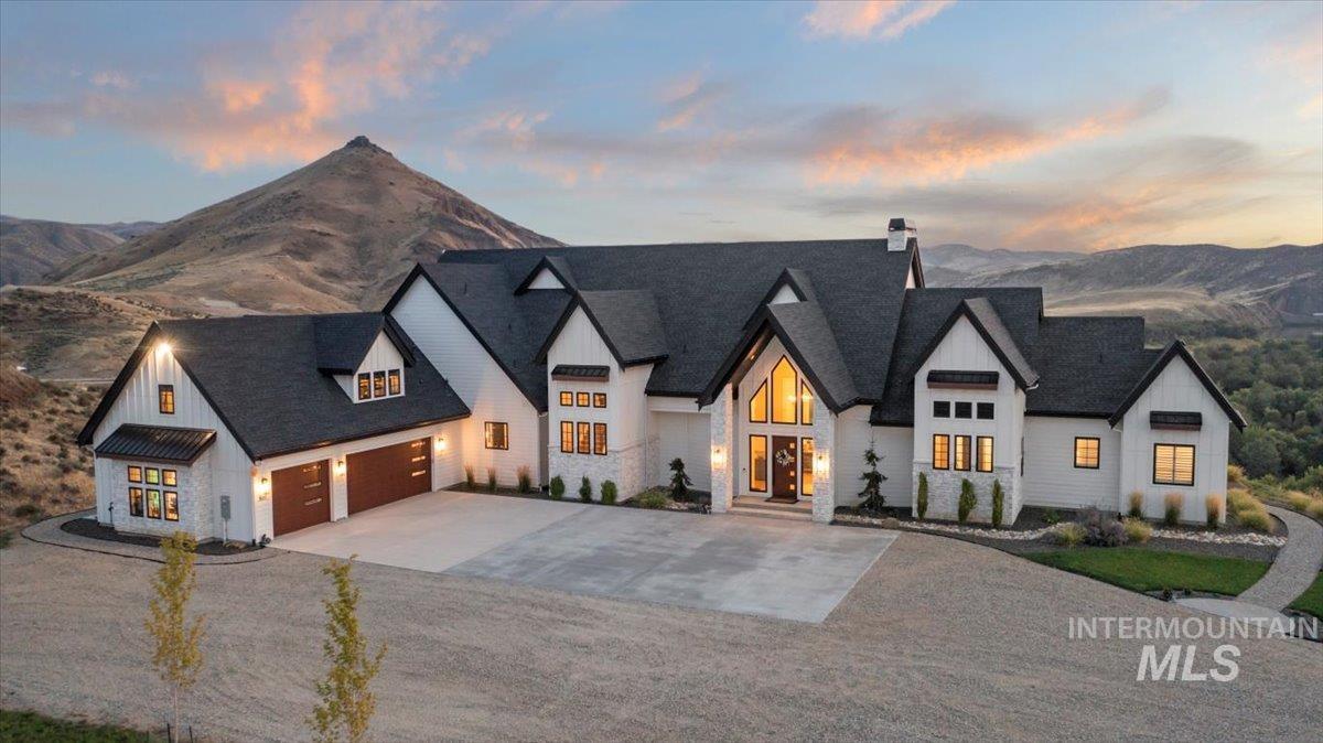 Modern farmhouse style home featuring board and batten siding, concrete driveway, a garage, and stone siding
