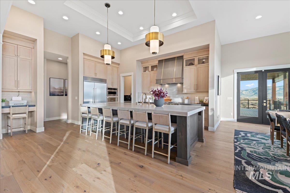 Kitchen with decorative backsplash, a tray ceiling, light wood finished floors, a breakfast bar, and a spacious island