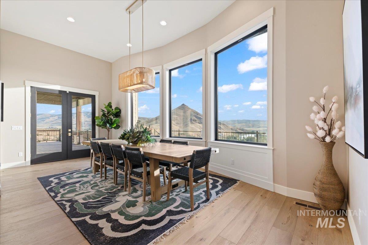 Dining area with french doors, light wood-style flooring, a mountain view, and recessed lighting