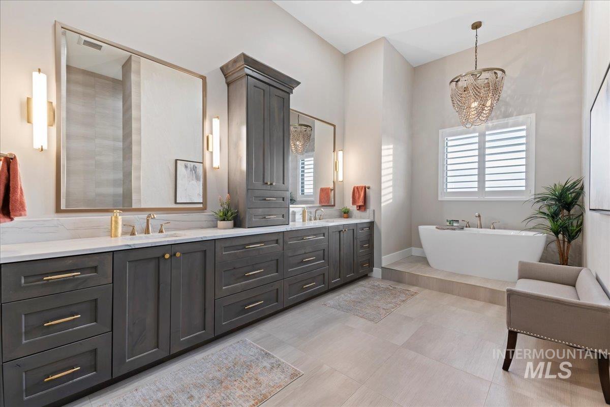 Full bath with double vanity, a freestanding bath, and a chandelier
