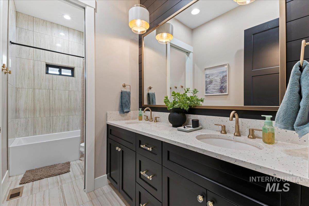 Full bathroom with bathing tub / shower combination, double vanity, recessed lighting, and light tile patterned flooring