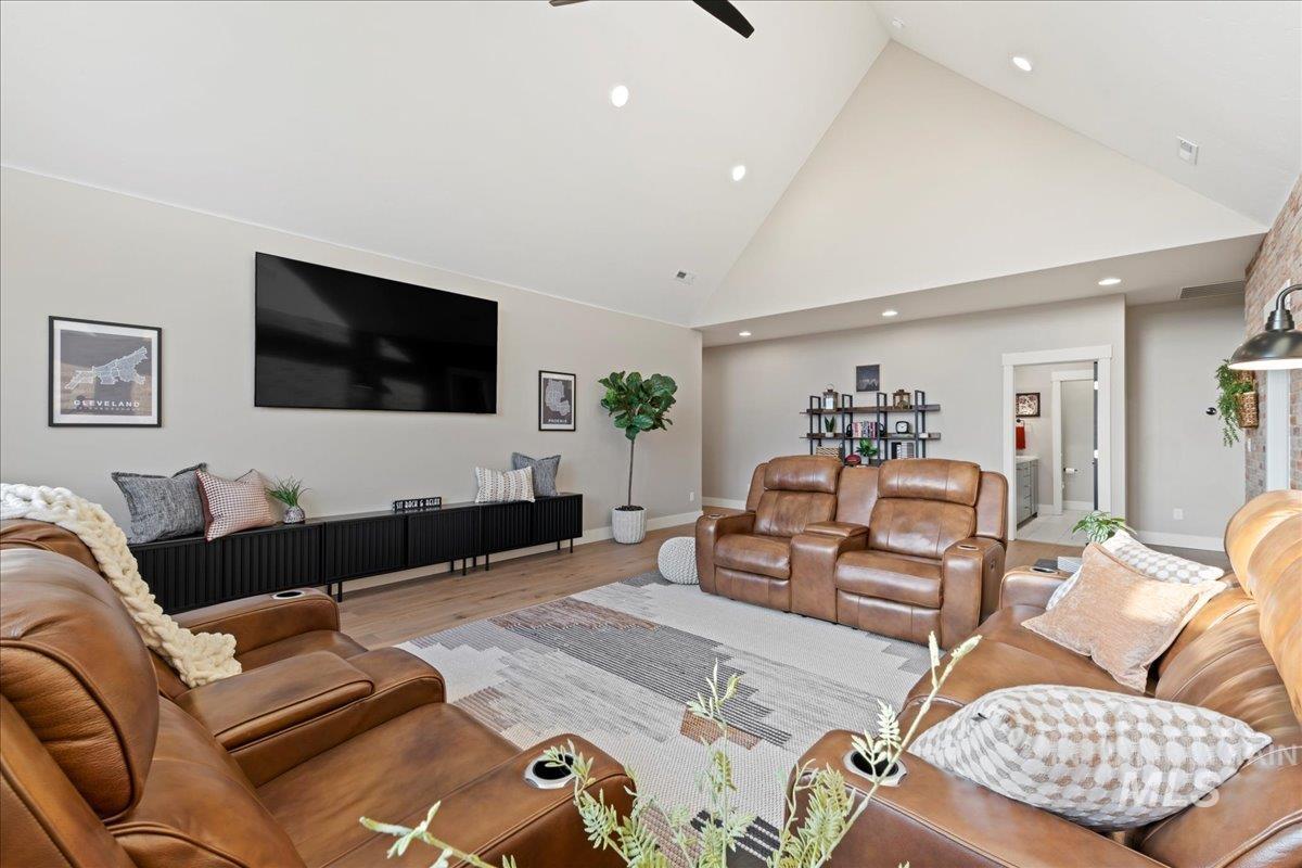 Living room featuring high vaulted ceiling, wood finished floors, a ceiling fan, and recessed lighting