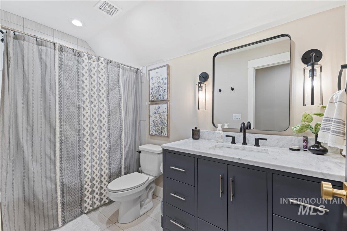 Full bathroom with vanity, a shower with curtain, recessed lighting, light tile patterned flooring, and vaulted ceiling