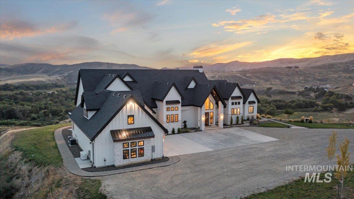 Modern farmhouse featuring board and batten siding, curved driveway, a mountain view, a chimney, and roof with shingles