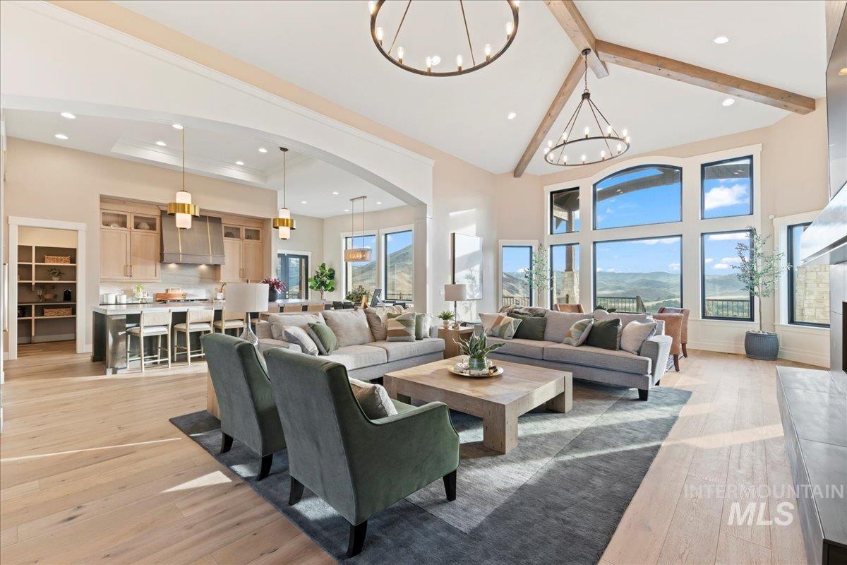 Living room with high vaulted ceiling, light wood-style flooring, healthy amount of natural light, beam ceiling, and arched walkways