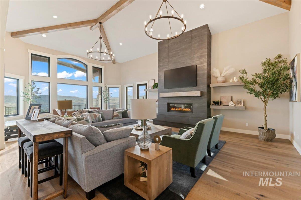 Living area featuring beamed ceiling, high vaulted ceiling, light wood finished floors, a tile fireplace, and recessed lighting