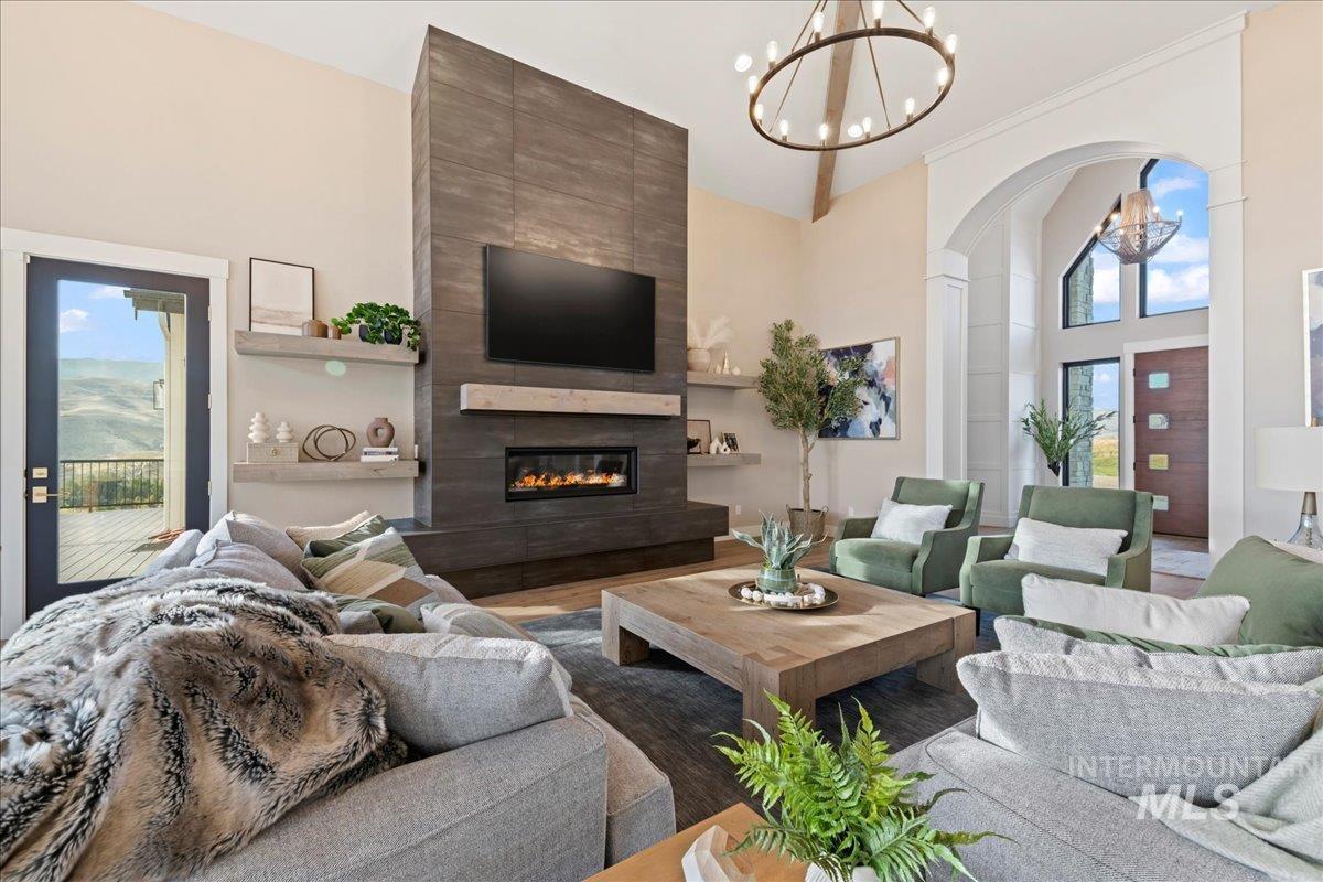 Living area with a towering ceiling, a chandelier, a fireplace, and wood finished floors