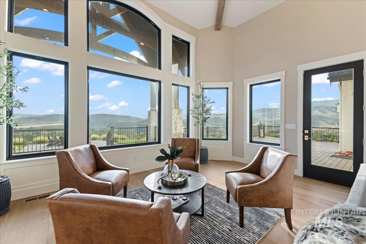 Sunroom with a mountain view, a towering ceiling, beamed ceiling, and wood finished floors