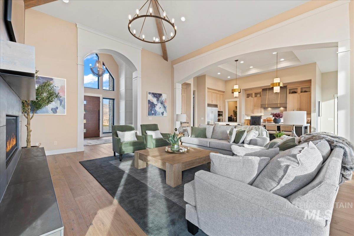 Living area featuring light wood-style floors, a glass covered fireplace, recessed lighting, a chandelier, and arched walkways