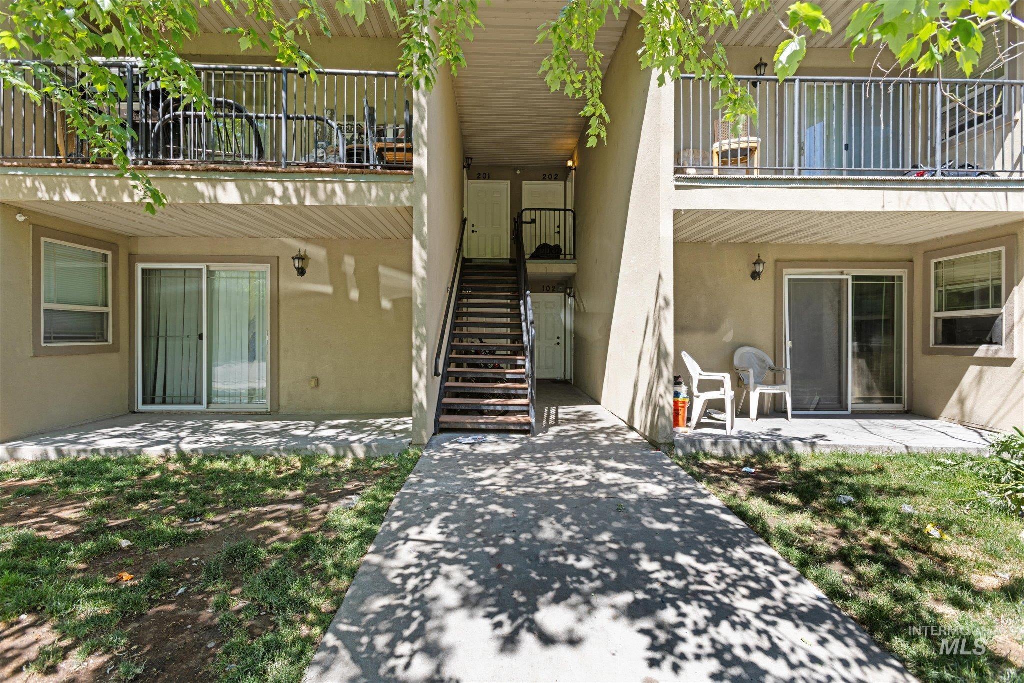 Entrance to property with a balcony, stucco siding, and a patio area