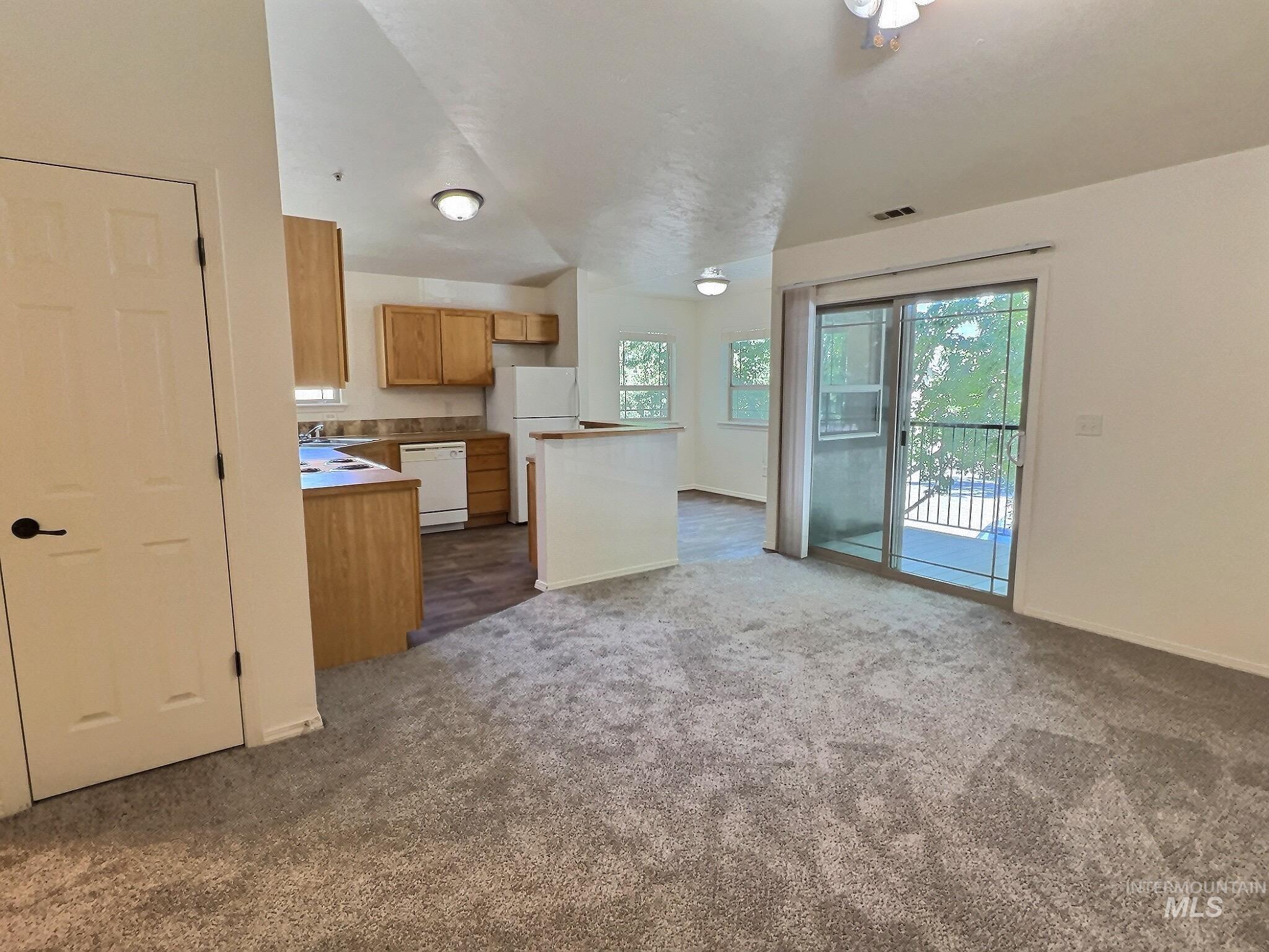 Kitchen featuring white appliances, dark carpet, and open floor plan