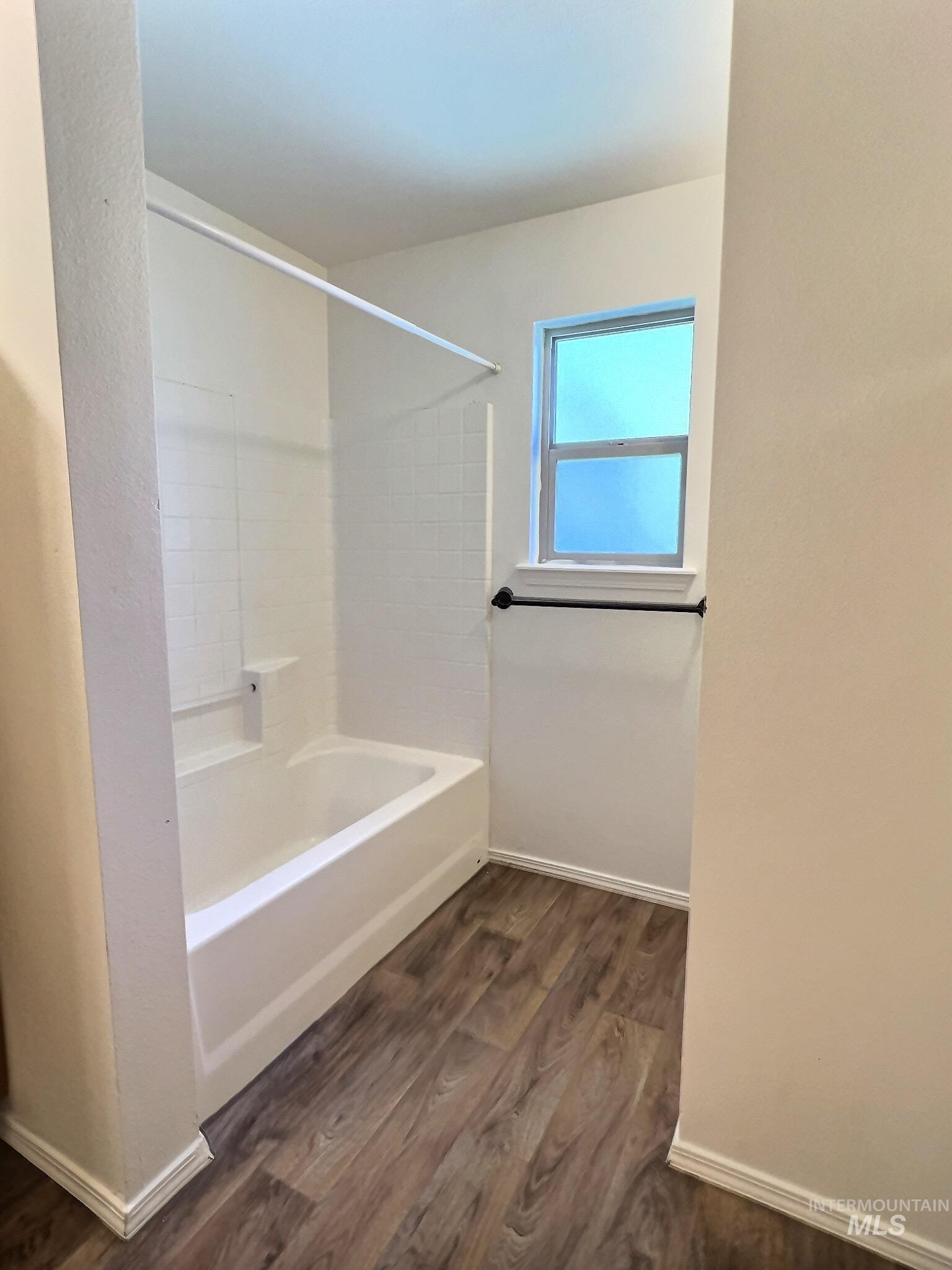 Bathroom with shower / bath combination and dark wood-type flooring