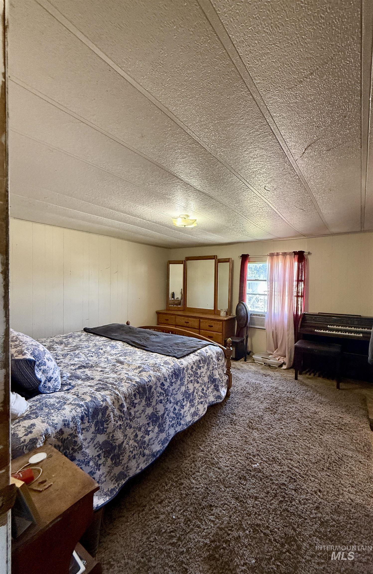 Carpeted bedroom with a textured ceiling and wood walls