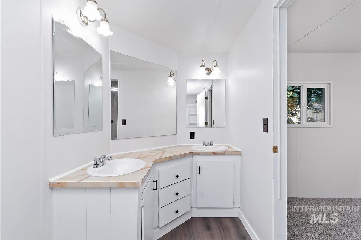 Bathroom with double vanity and dark wood-type flooring