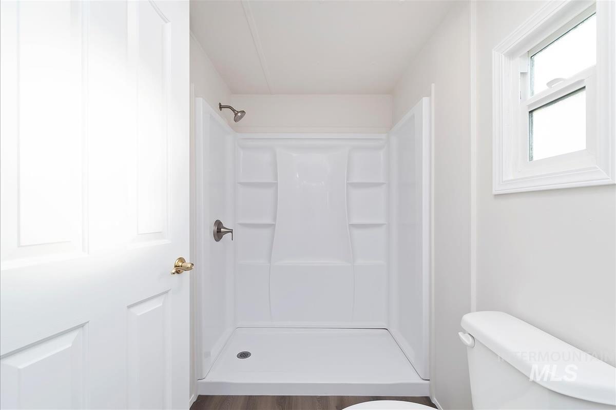Full bath with toilet and a shower stall