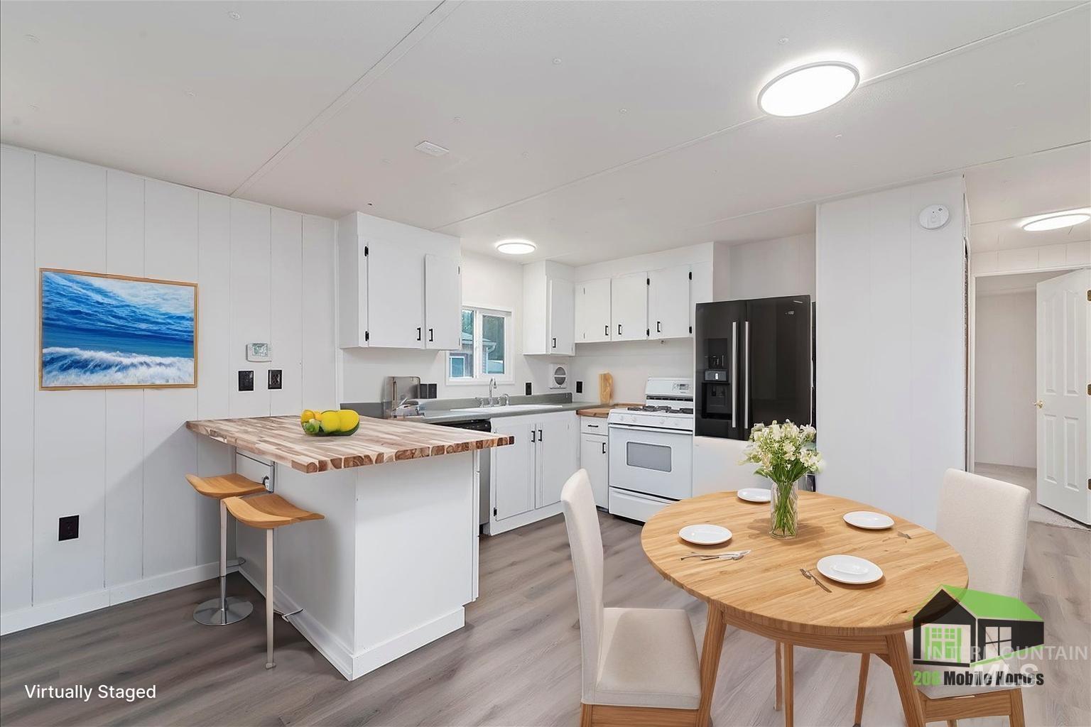 Kitchen featuring wooden counters, a breakfast bar area, black refrigerator with ice dispenser, gas range gas stove, and white cabinets
