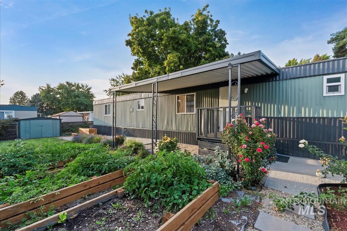 Back of property with a storage unit and a garden