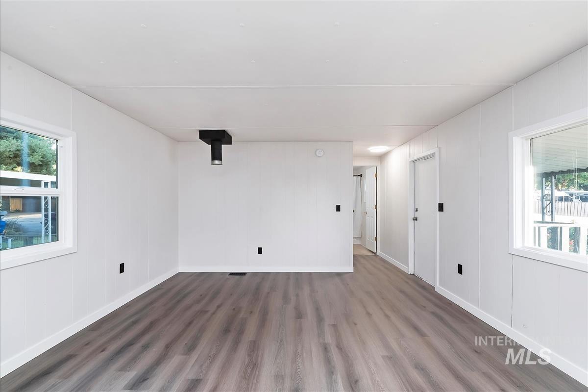 Spare room featuring plenty of natural light, dark wood-type flooring, and a wood stove