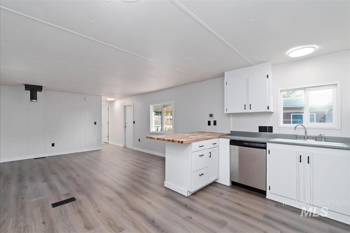 Kitchen featuring a peninsula, butcher block countertops, open floor plan, dishwasher, and light wood finished floors