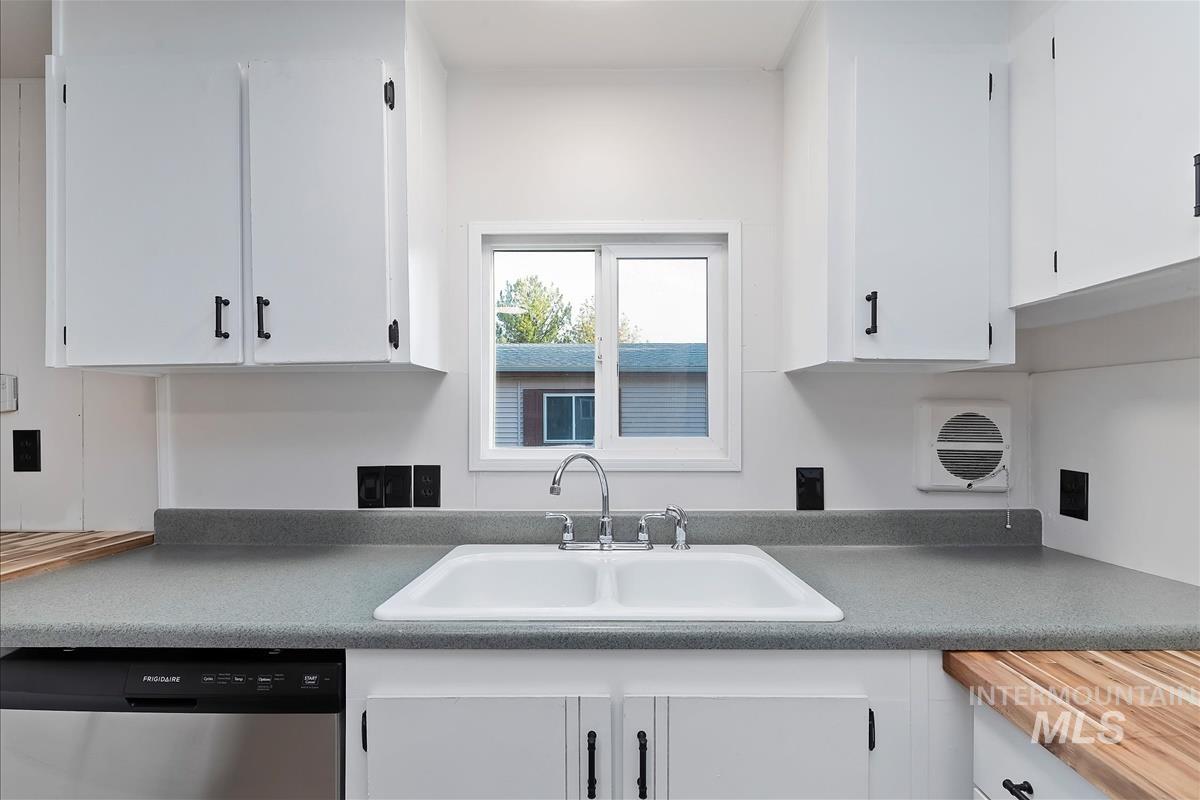Kitchen with stainless steel dishwasher and white cabinetry