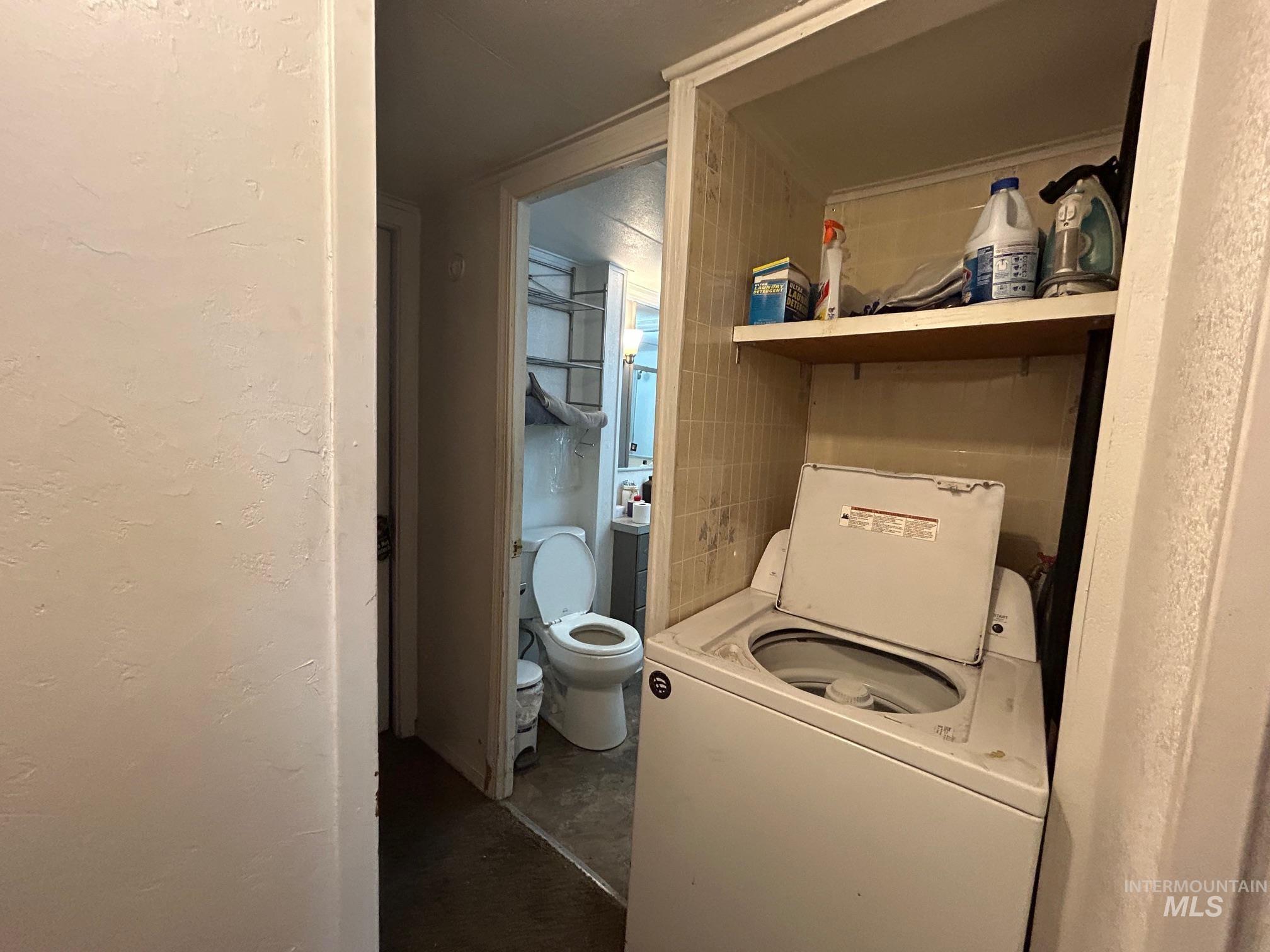 Laundry area with washer / clothes dryer and a textured wall