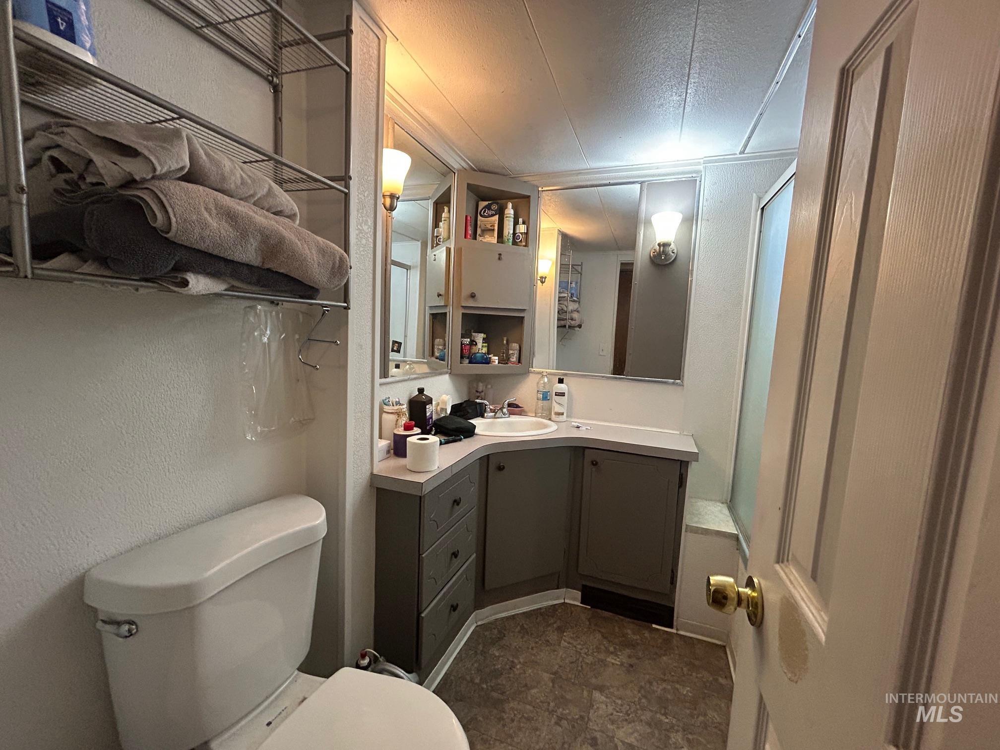 Full bath featuring vanity, a textured wall, a textured ceiling, and stone finish floors