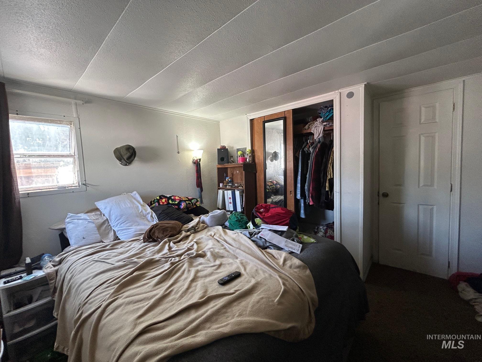 Bedroom with a textured ceiling, a closet, and carpet