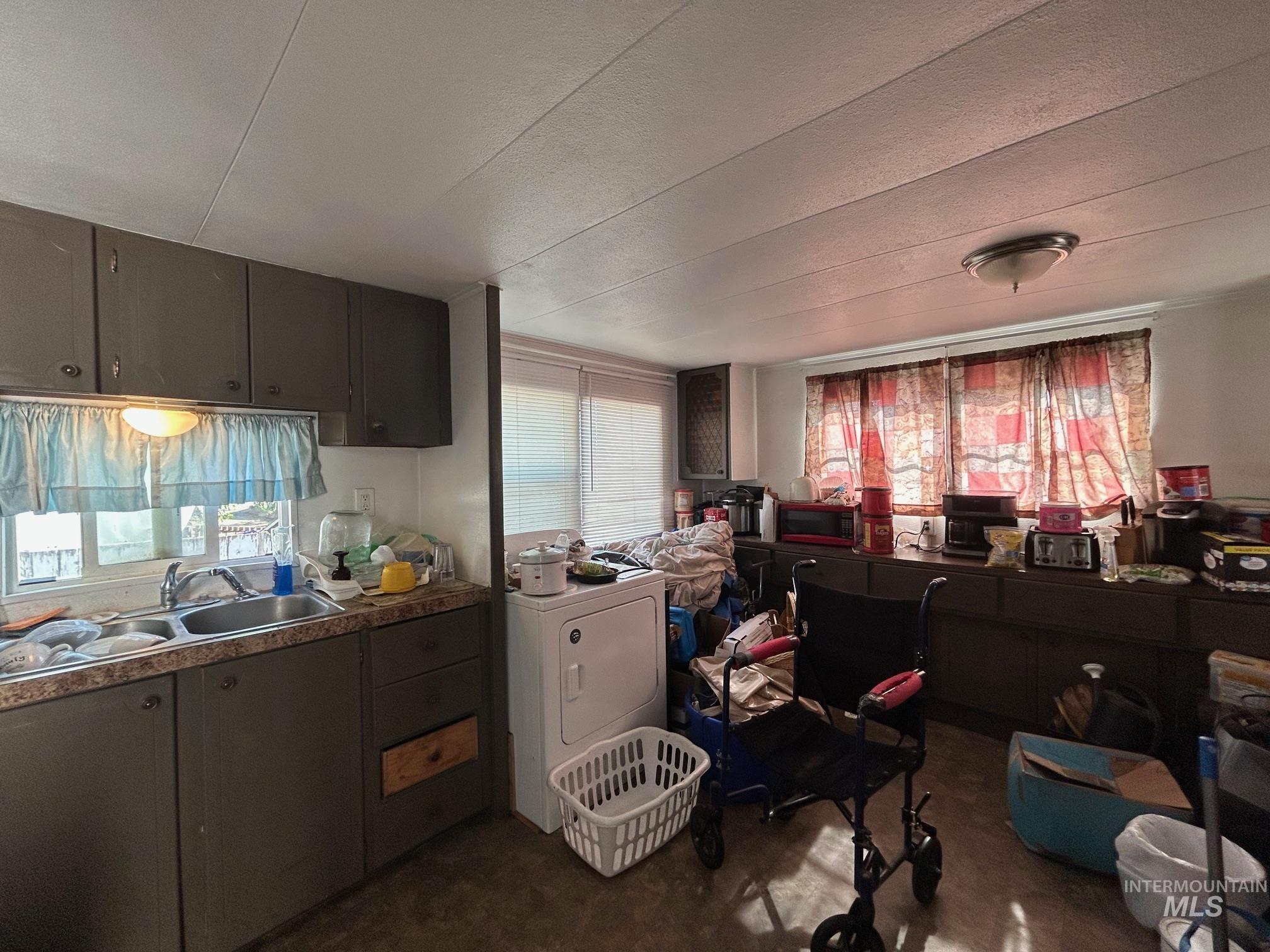 Kitchen with washer / clothes dryer, plenty of natural light, a textured ceiling, and dark brown cabinetry
