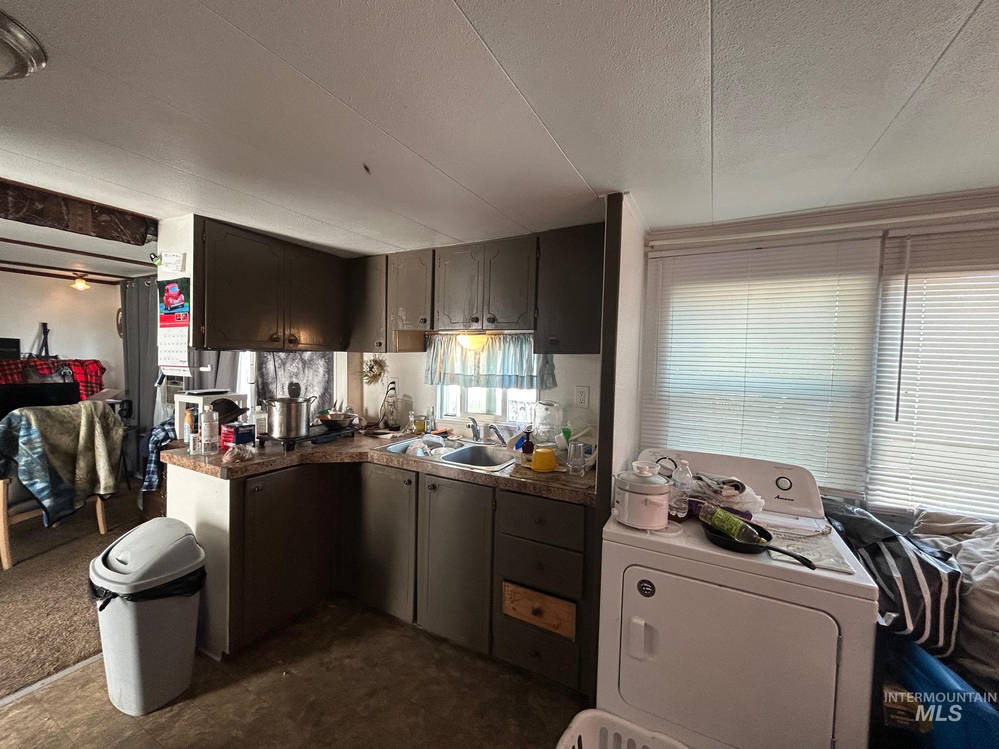 Kitchen featuring washer / dryer, a textured ceiling, and dark countertops