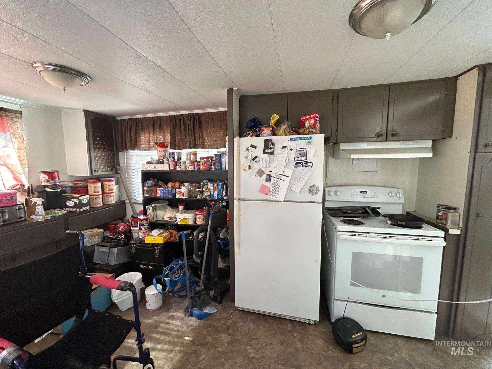 Kitchen featuring white appliances, under cabinet range hood, and healthy amount of natural light