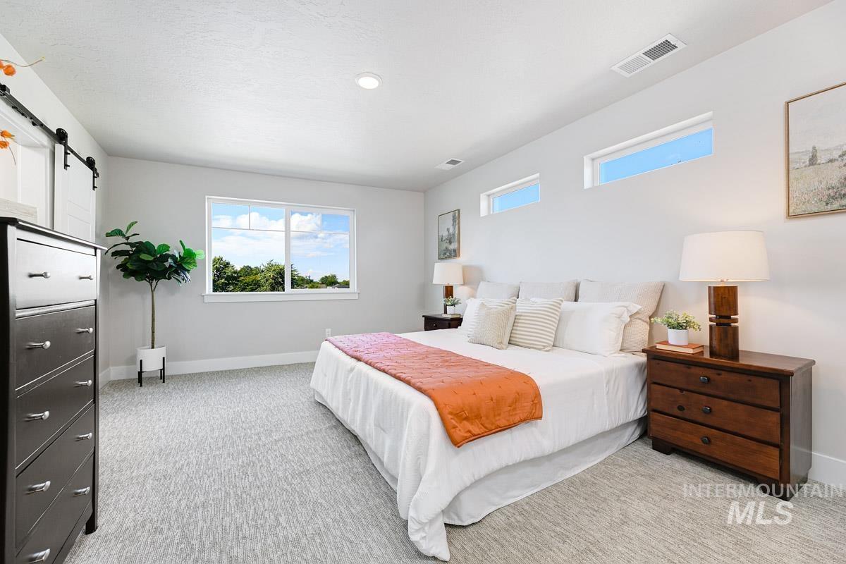 Bedroom featuring a barn door and light colored carpet