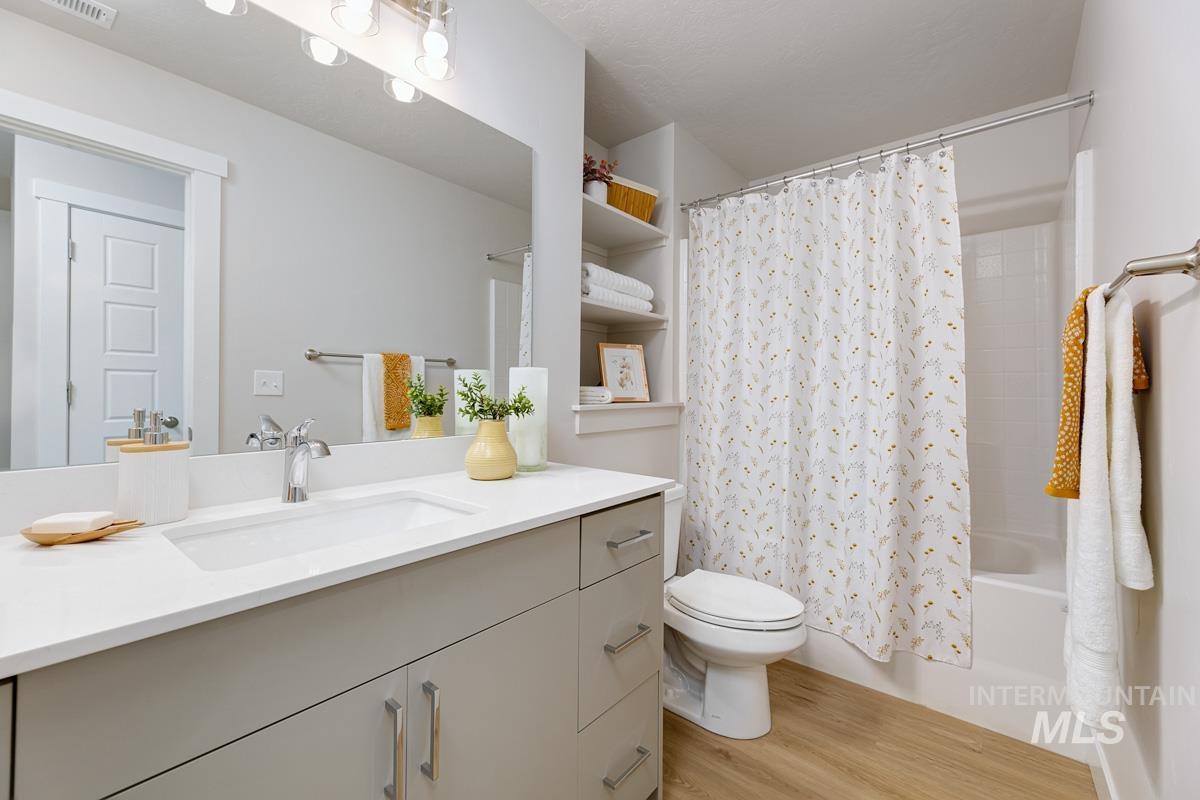 Full bath with shower / tub combo with curtain, light wood finished floors, and vanity