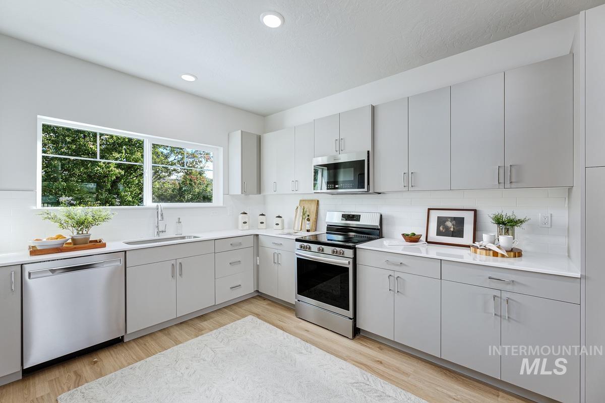 Kitchen with decorative backsplash, appliances with stainless steel finishes, light wood-style floors, and recessed lighting