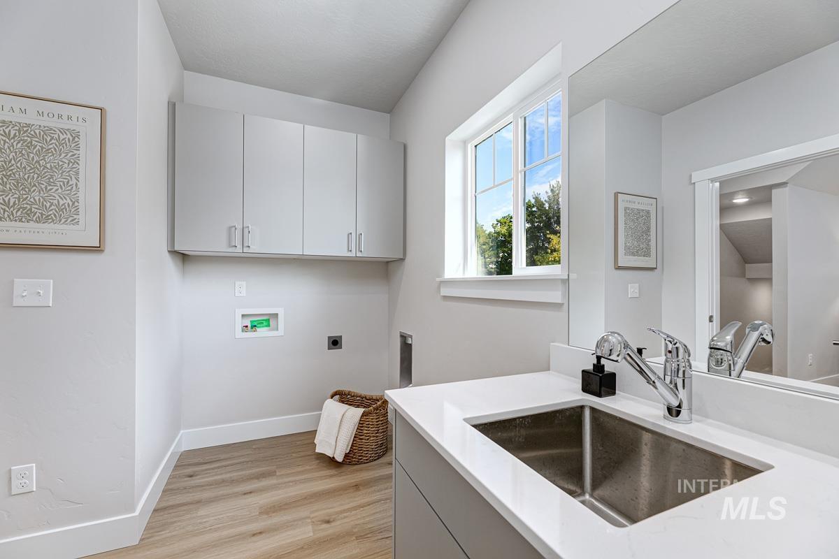Washroom featuring washer hookup, electric dryer hookup, light wood-style floors, and cabinet space