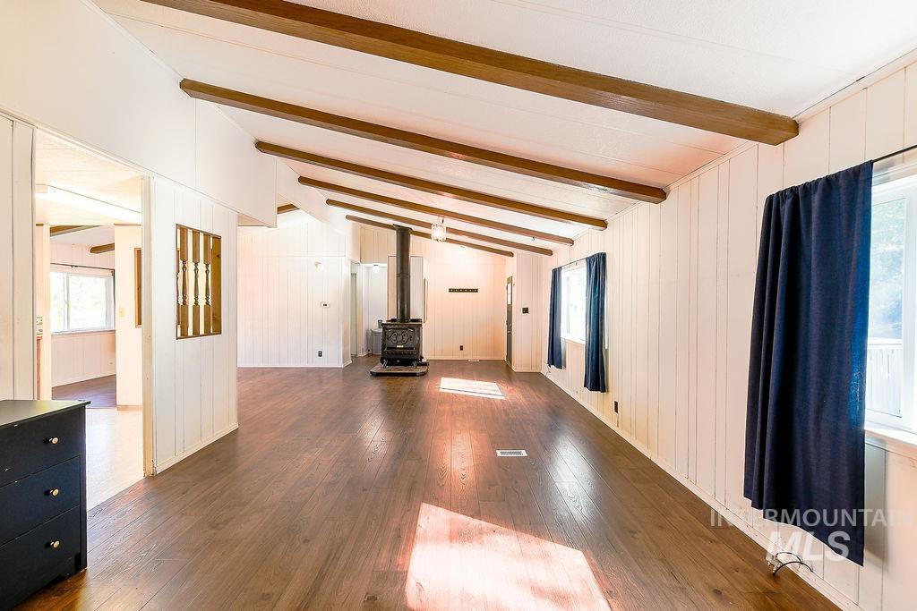Unfurnished living room with plenty of natural light, a wood stove, hardwood / wood-style flooring, and wood walls