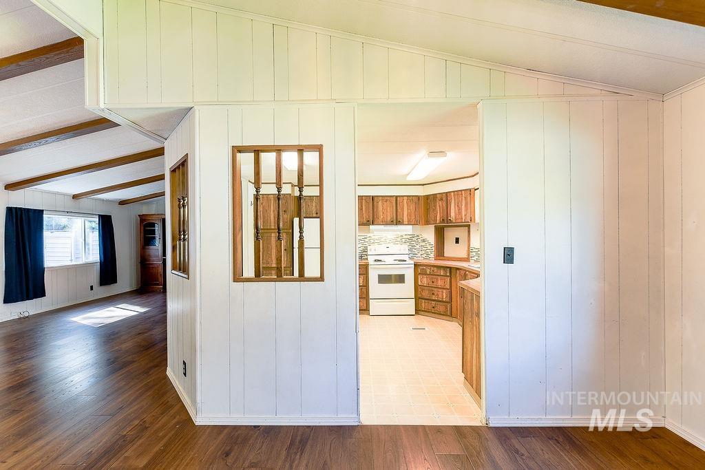 Kitchen with brown cabinets, wooden walls, light countertops, white appliances, and light wood-type flooring